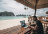 The Ultimate Guide to Being a Successful Digital Nomad Over 30 Digital Nomad in Thailand, a modern traveler settled in a beachside café, laptop open amidst tropical drinks