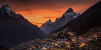 Namche Bazaar Sunset, the terraced village carved into the mountainside, bathed in a warm orange glow, distant snow-capped peaks of the Himalayas