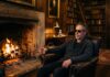 The Cold Stone Cure: Why the Highlands Turn Up the Heat Luxury solo travel retreats guest sitting fireside in a candlelit Scottish Highland drawing room