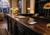 Your next hotel may be booked by a chatbot. Who is it working for? Smartphone glowing with a chat screen on an empty hotel reception desk, illustrating AI hotel booking